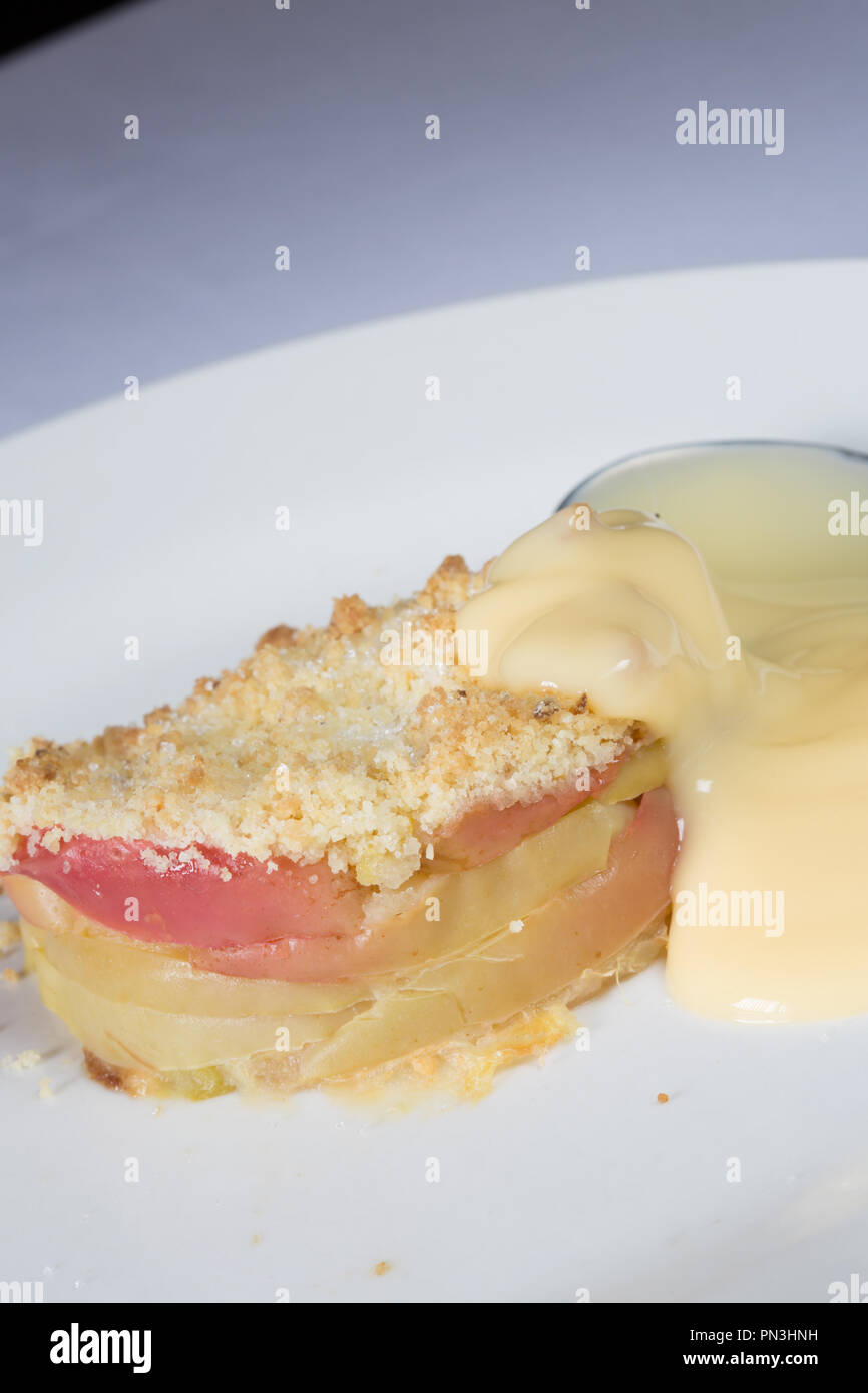 Classic English dessert of Apple crumble with Custard sauce Stock Photo
