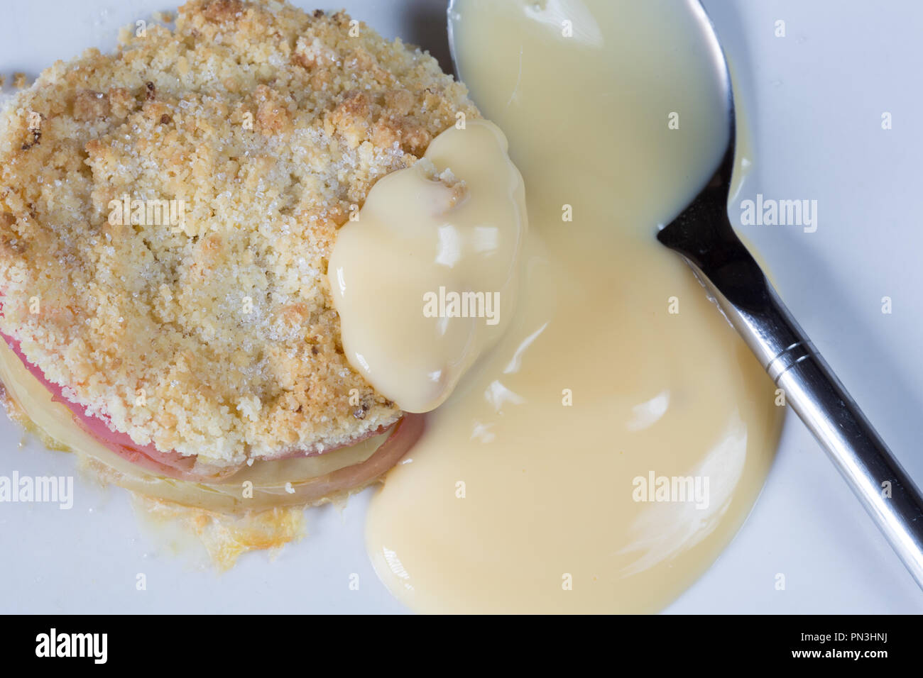 Classic English dessert of Apple crumble with Custard sauce Stock Photo