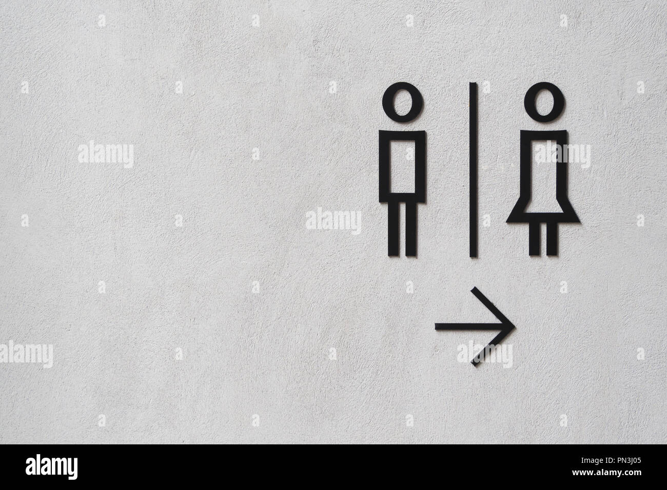 modern man and woman public toilet sign on the cement wall with copy space. public restroom sign at the loft style cement wall. Stock Photo