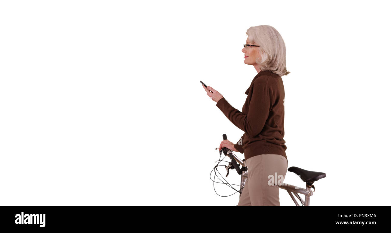 Old white lady standing with bicycle using smartphone on white copy space Stock Photo