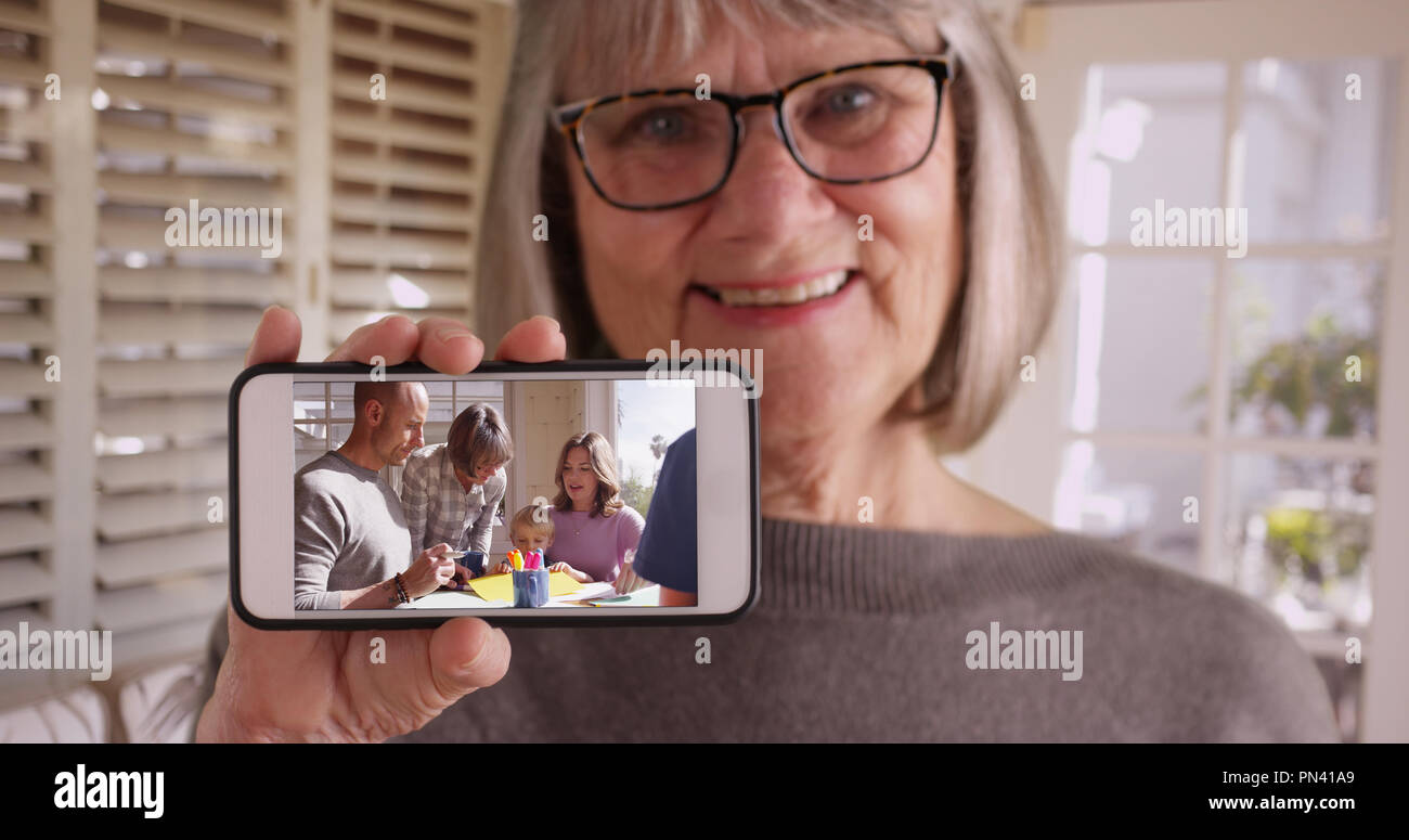 Grandmother showing off footage of her spending time with family on smartphone Stock Photo