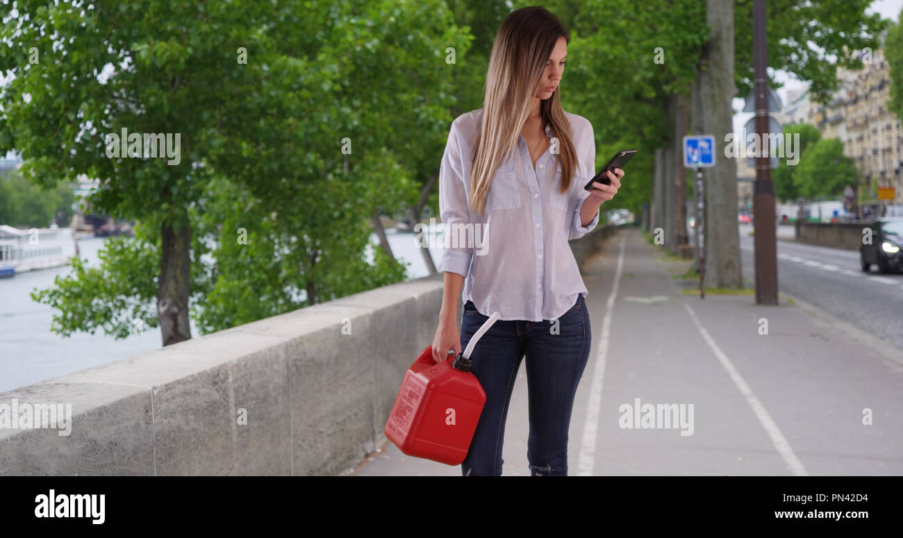 Woman With Plastic Jerrycan Using Phone To Find Nearest Gas