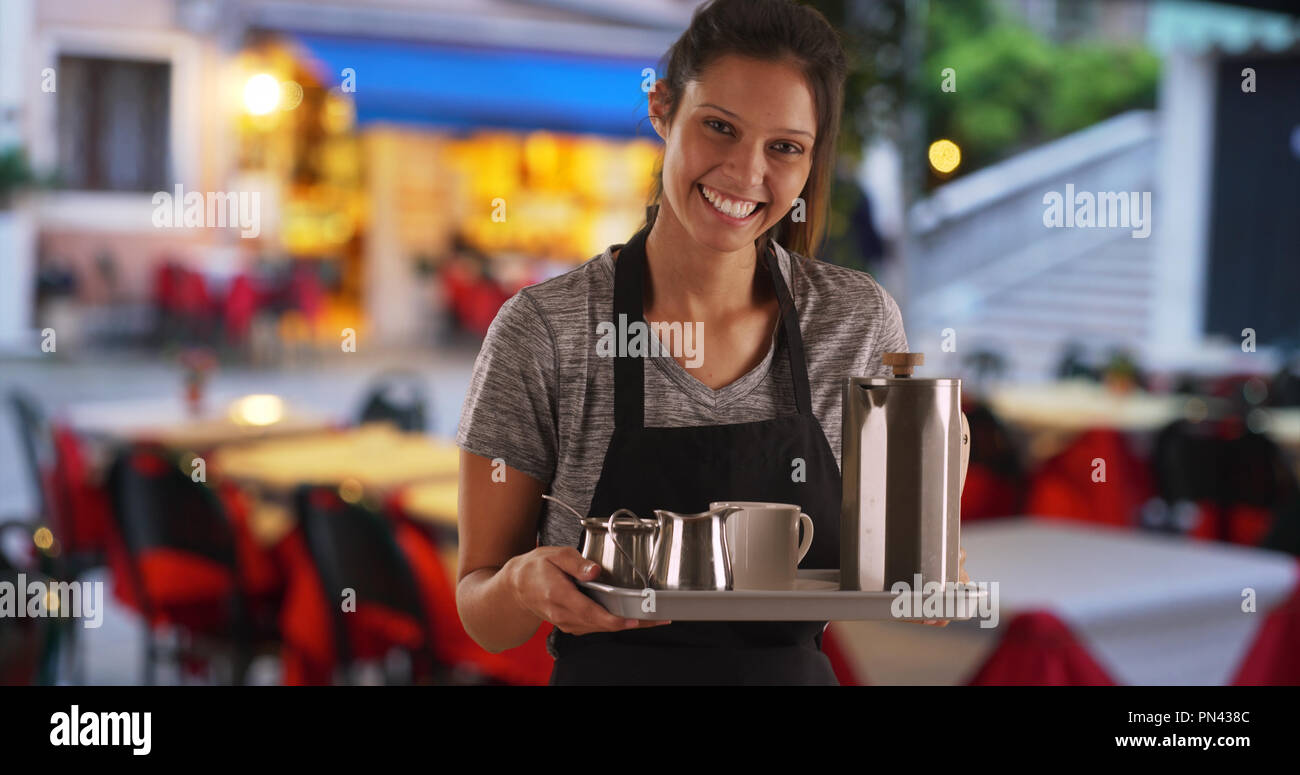 Pretty waitress carrying tray to serve drinks at coffee shop or