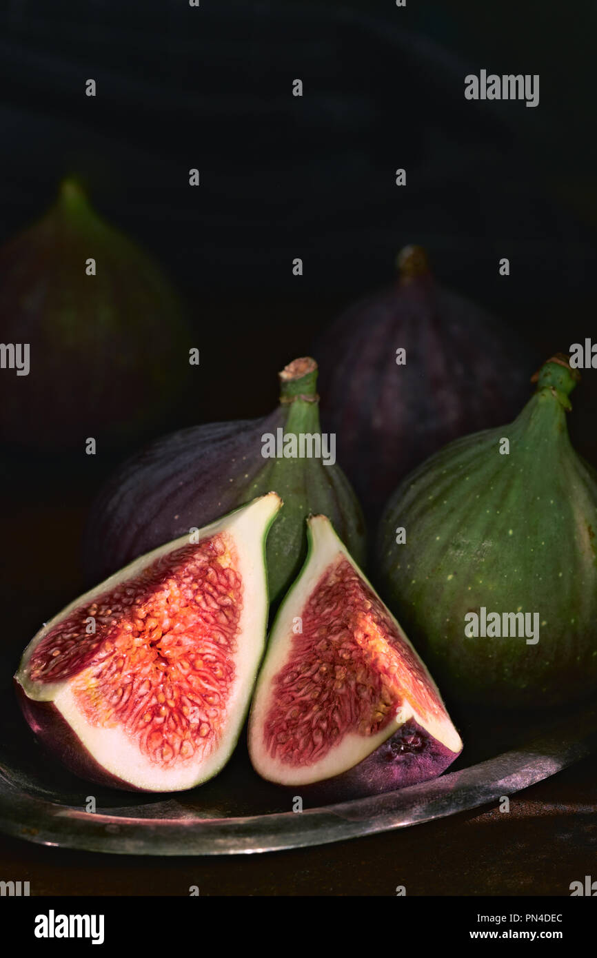 quartered green figs on dark background, space for your text Stock