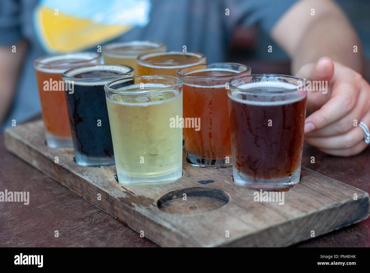 Flight of seven different beers served in small glasses on a wooden tray Stock Photo