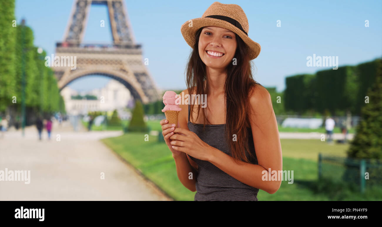 Beautiful young tourist woman holding ice cream cone near Eiffel Tower
