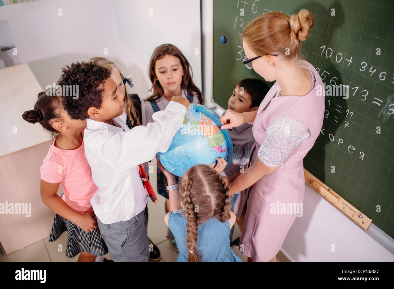 schoolchilds looking at globe with teacher at geography lesson Stock Photo