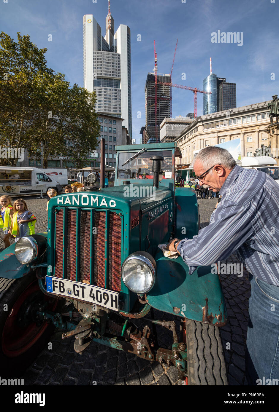 20 September 2018, Hessen, Frankfurt Main: Rüdiger Witzel, chairman of the vintage car association for historic agricultural machinery from Hungen, cleans his 1948 Hanomag R40 in front of the skyscraper backdrop at the 35th Frankfurt Harvest Festival in the city centre. The aim of the event is to bring agriculture and rural life closer to the urban population. Photo: Frank Rumpenhorst/dpa Stock Photo