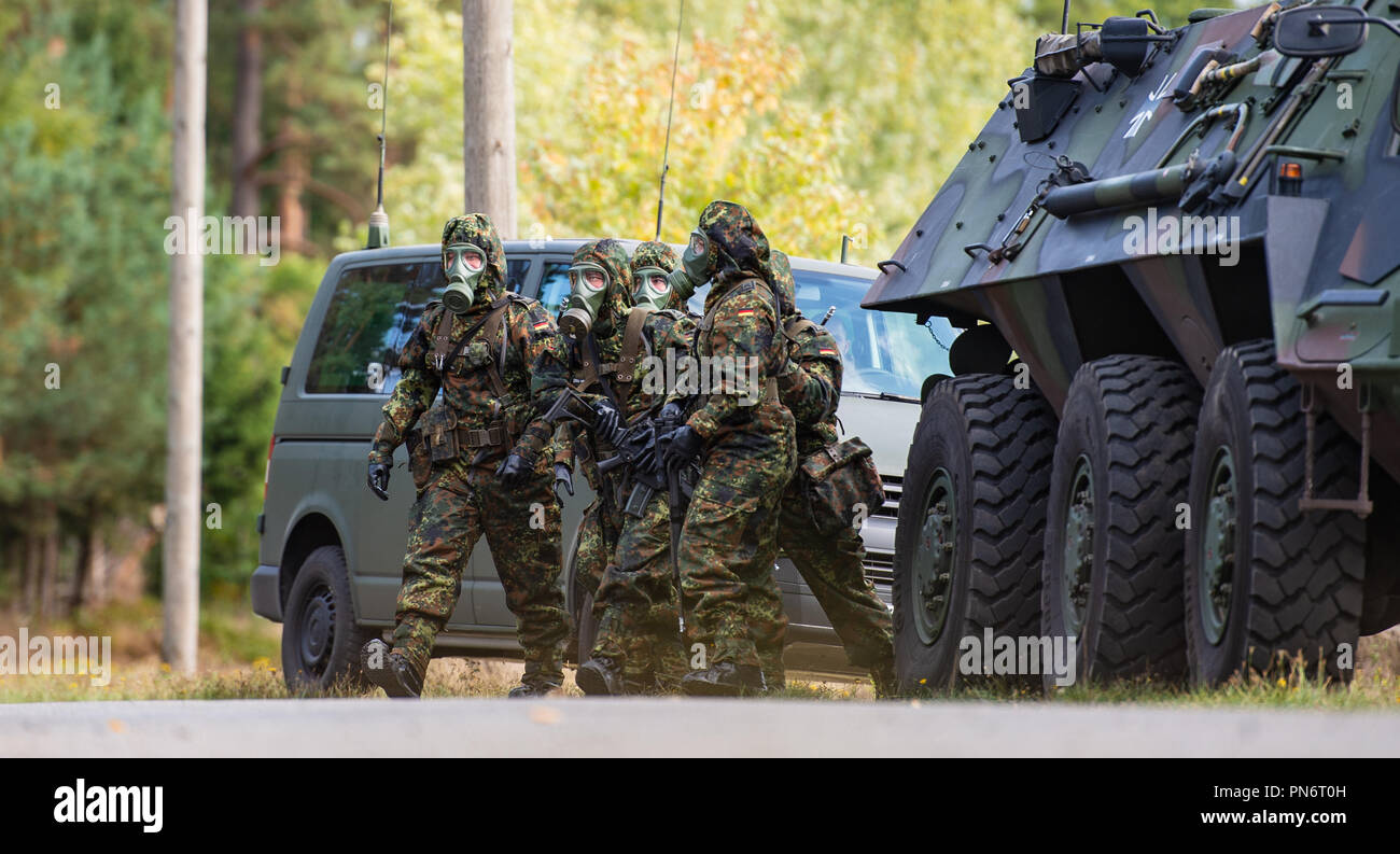 20 September 2018, Lower Saxony, Lohheide: Soldiers in protective suits and NBC protective masks leave their vehicles during the exercise 'CORONAT MASK'. A total of 1300 soldiers from 14 nations in 4 countries have participated in the international NBC defence exercise 'CORONAT MASK' since September 14, 2018. Photo: Philipp Schulze/dpa Stock Photo