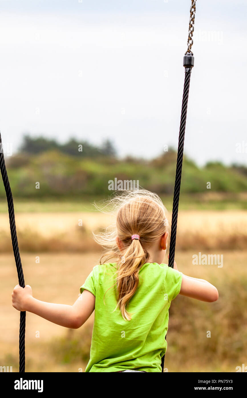 Little girl having fun standing on outdoor swing. Stock Photo