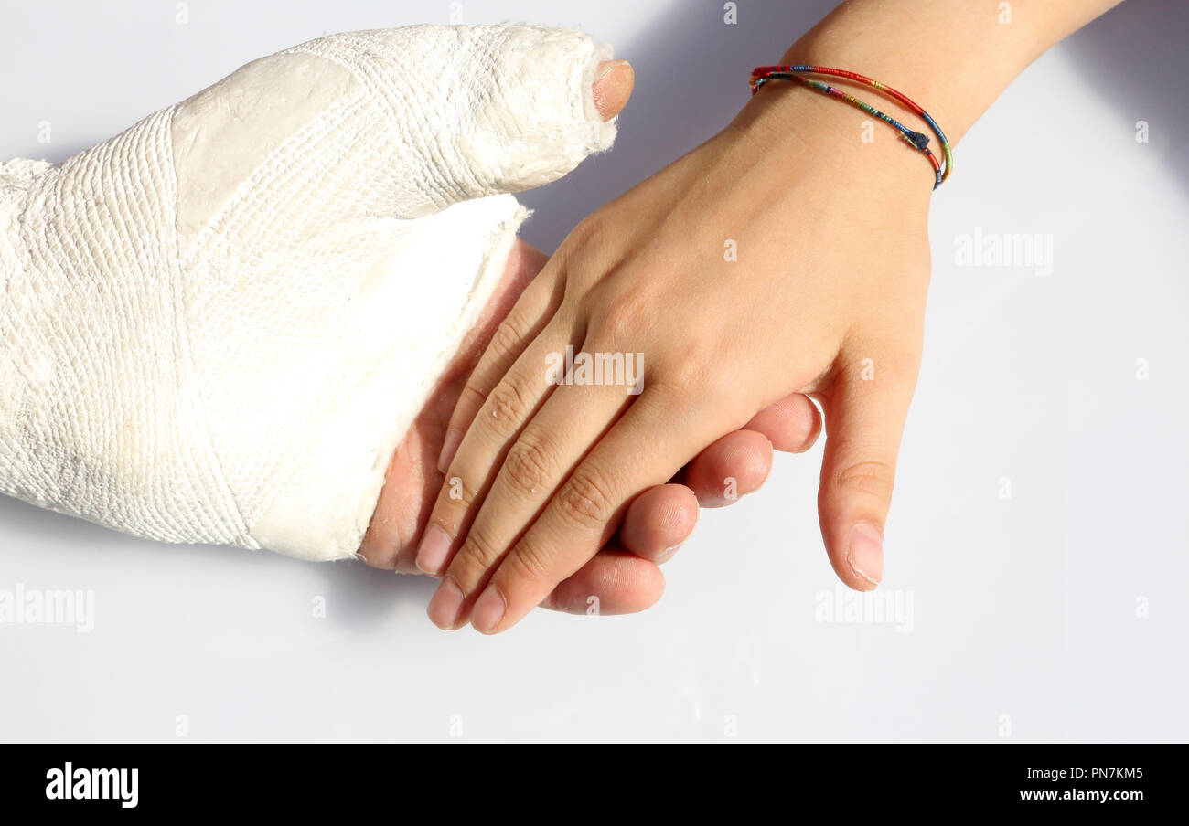 man with a fractured hand and a plaster cast at the hospital and the hand of his little girl Stock Photo