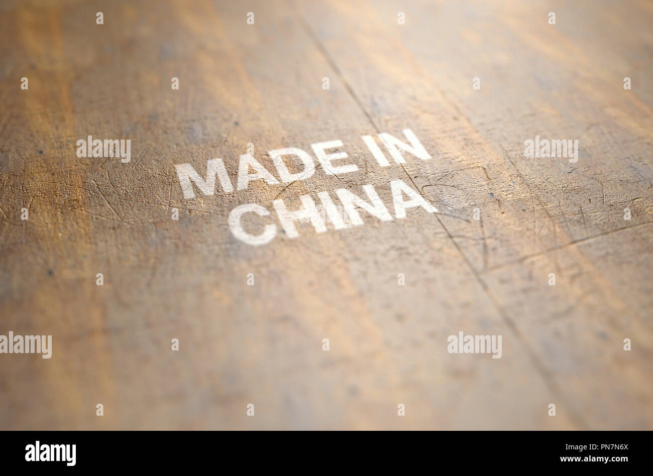 An extreme close up of a worn print sign that reads made in china on a flat wooden product surface - 3D render Stock Photo