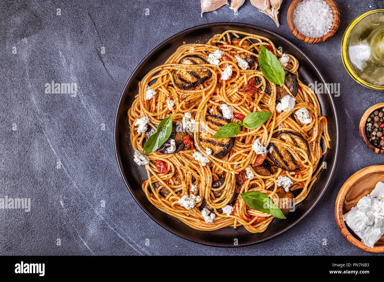 Pasta alla Norma traditional Italian food with eggplant, tomato, cheese and basil, top view