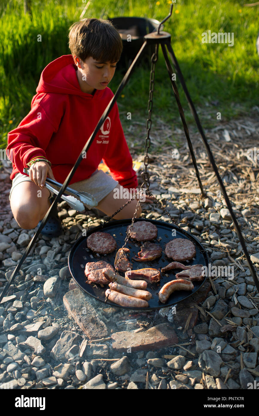 A young boy cooking on an open camp fire. Stock Photo