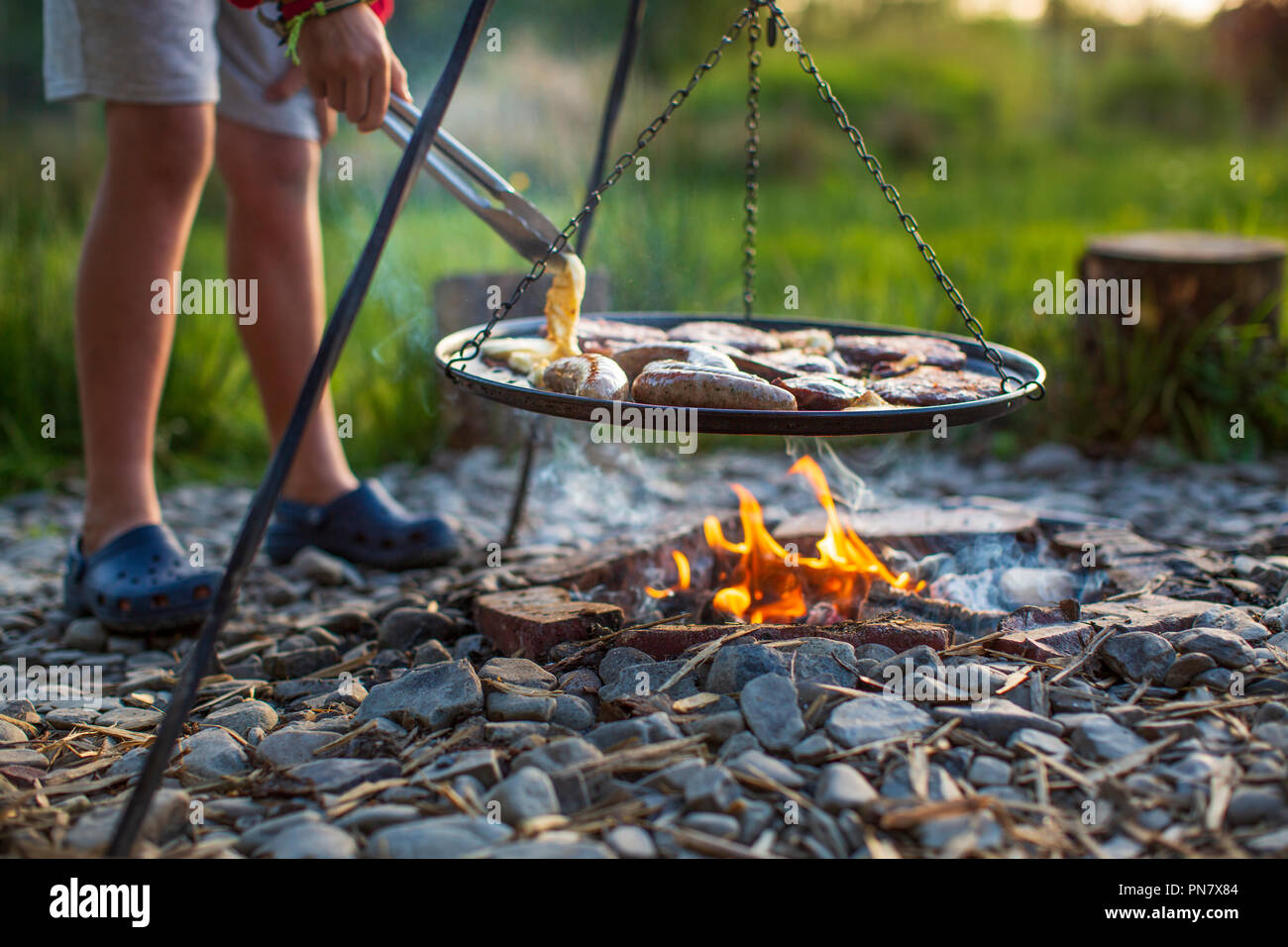 A young boy cooking on an open camp fire. Stock Photo