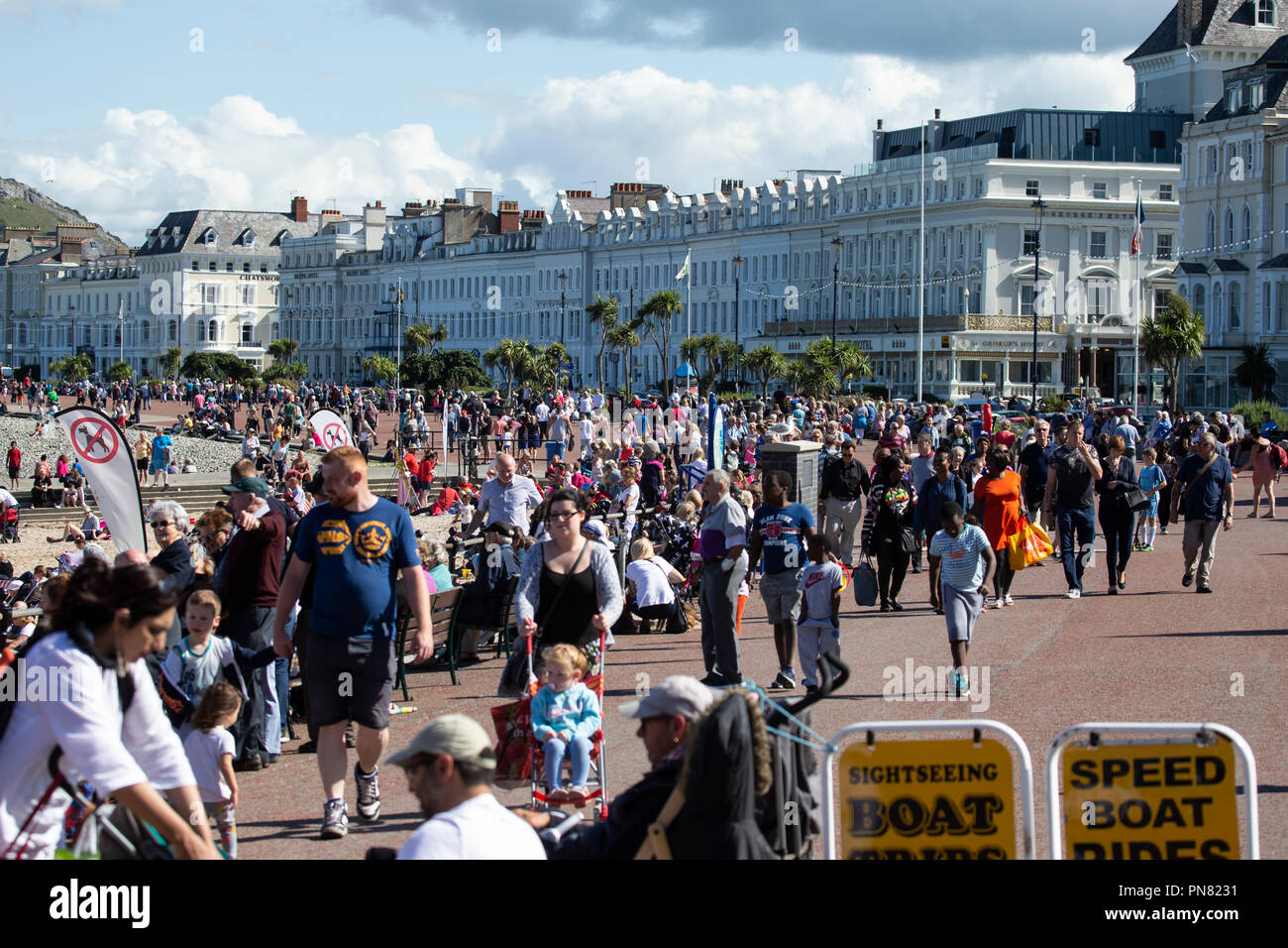 Hundreds of holiday makers enjoying the warm weather on the north shore promenade in Llandudno, North Wales Stock Photo