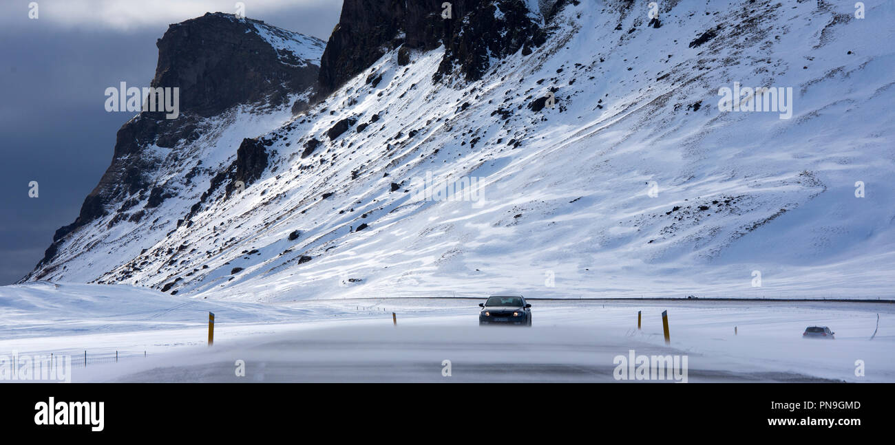 Drifting snow makes motoring conditions difficult  by snow-covered mountains along the main ring road from Reykjavik, South Iceland Stock Photo