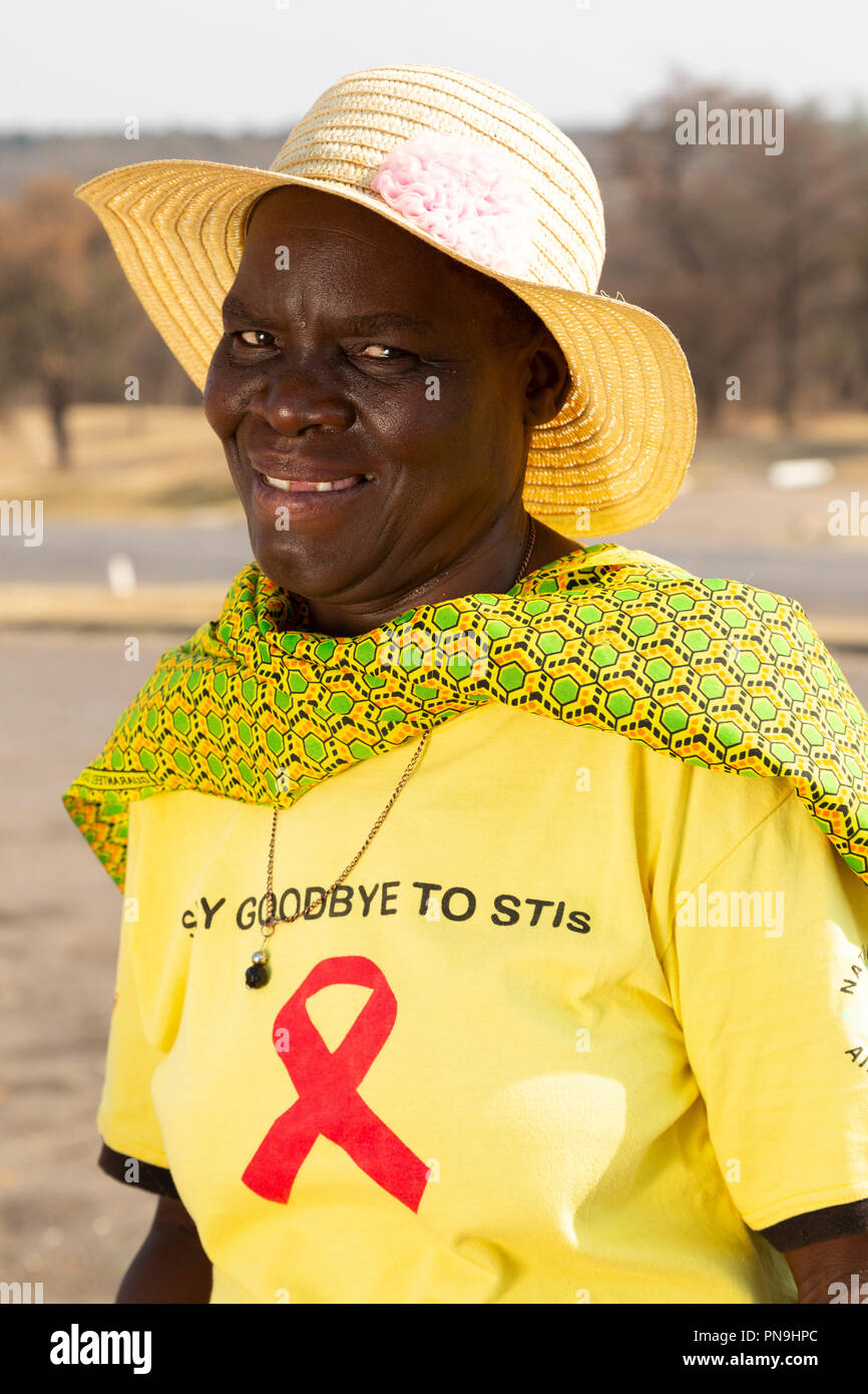 A woman in a yellow T-shirt and bush hat in Zimbabwe. Her T-shirt bears a message raising awareness about sexually transmitted diseases. Stock Photo