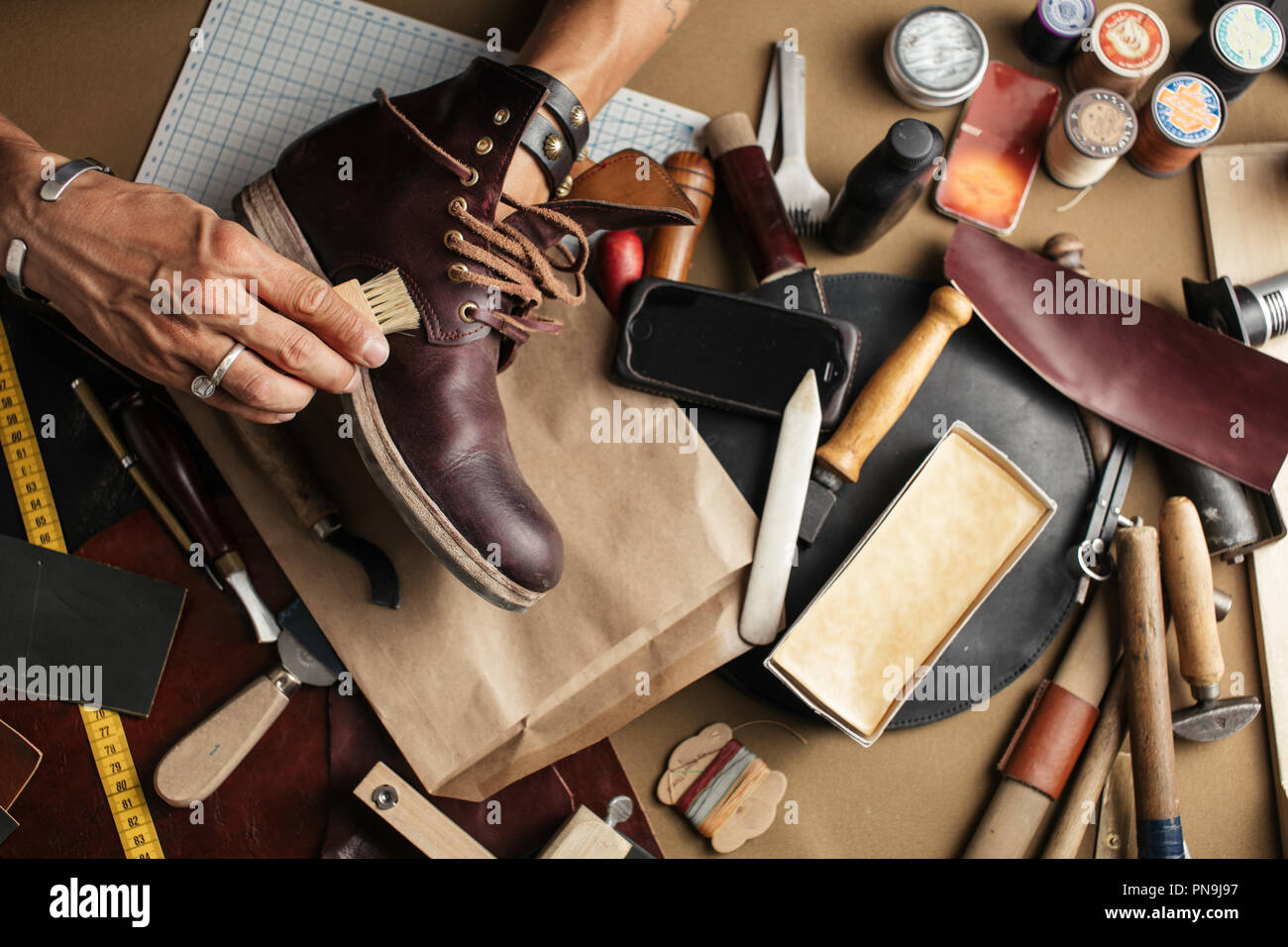 Close up of shoe maker hands producing boots in his leather workshop Stock Photo