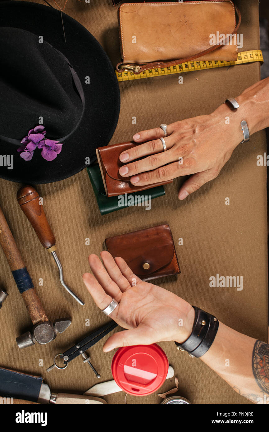 Leather goods master and handmade leather wallets. Workflow in the workshop. Stock Photo