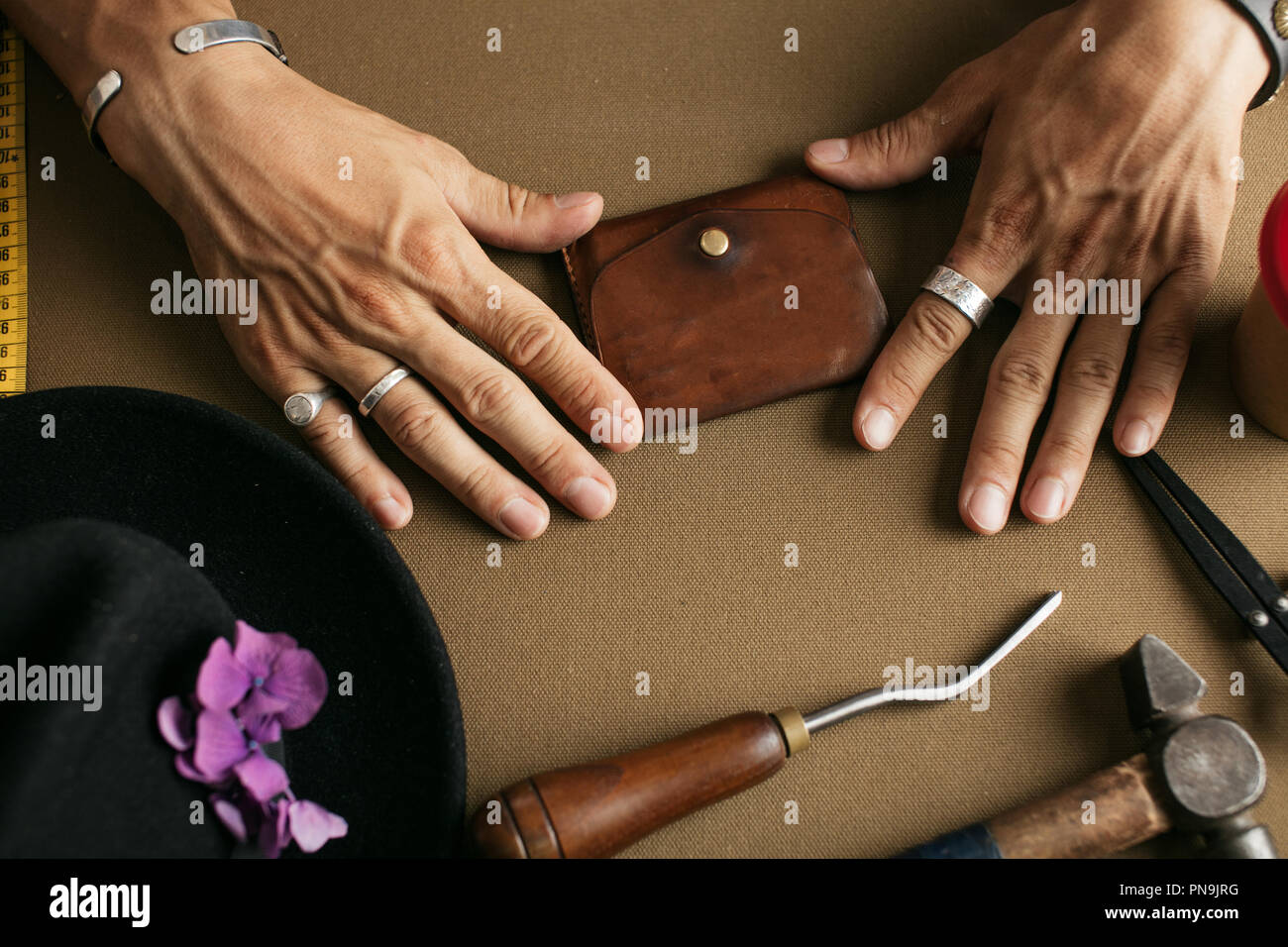 Leather goods master and handmade leather wallets. Workflow in the workshop. Stock Photo