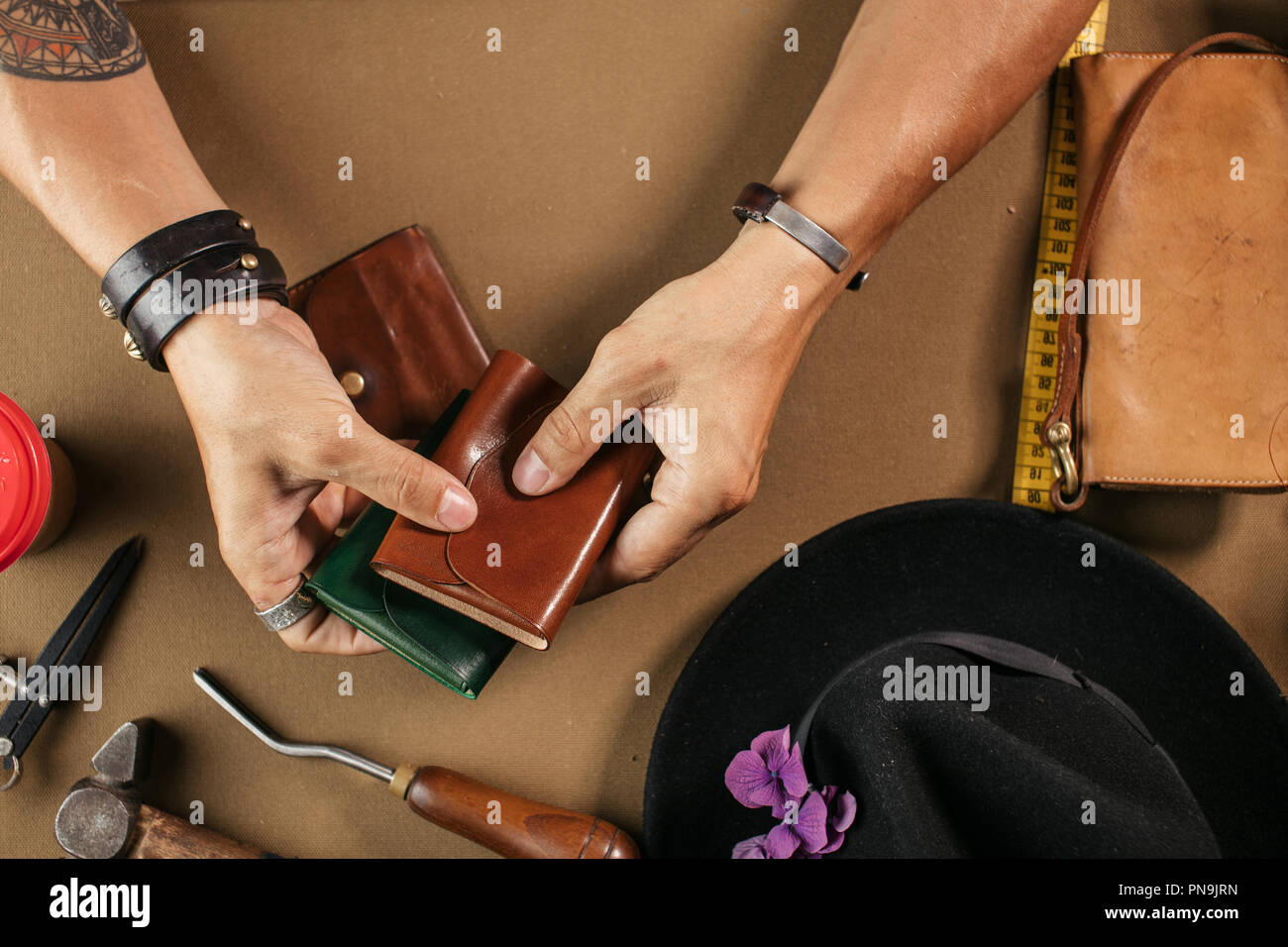 Leather goods master and handmade leather wallets. Workflow in the workshop. Stock Photo