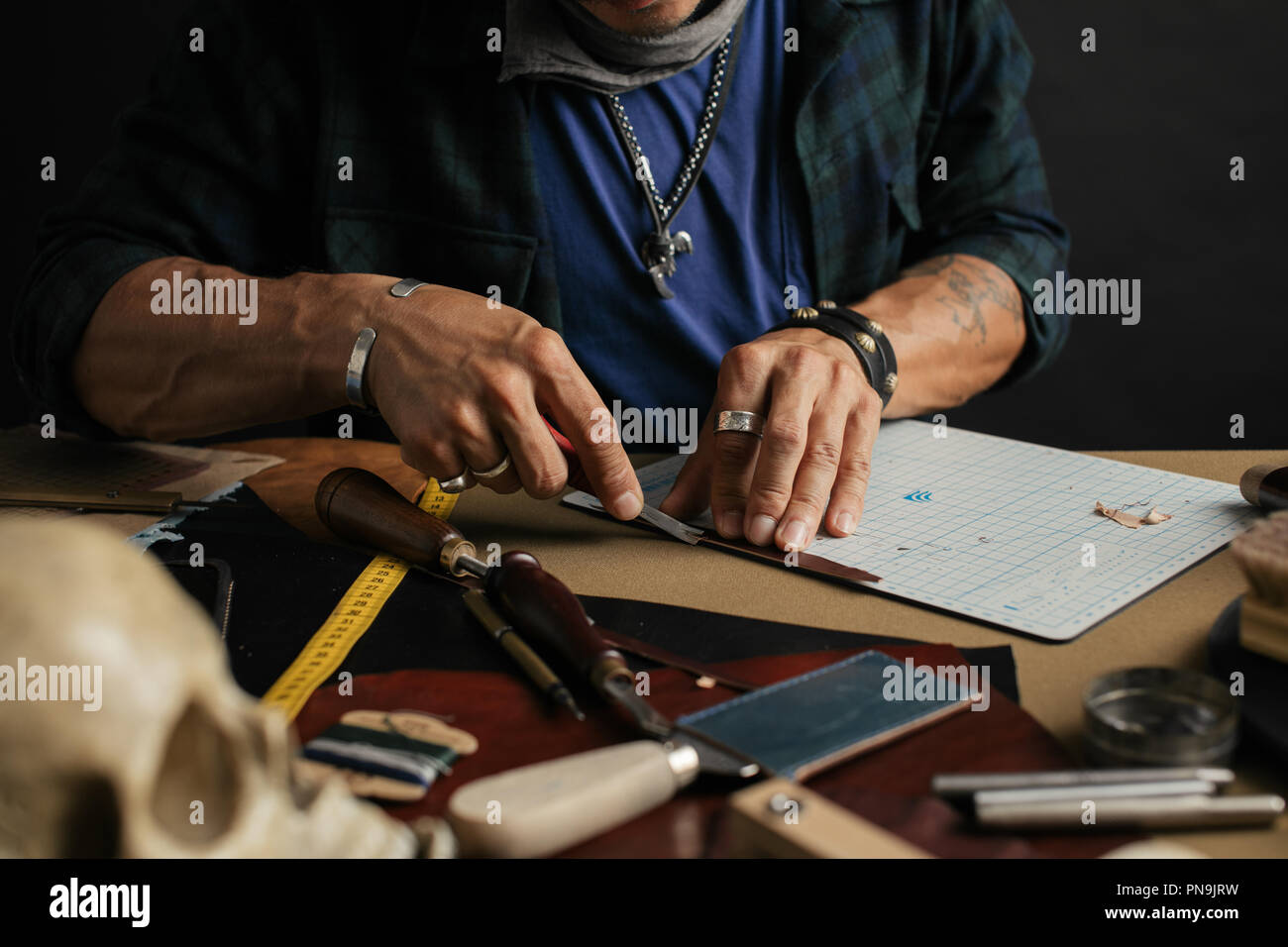 Leather goods master and handmade leather wallets. Workflow in the workshop. Stock Photo