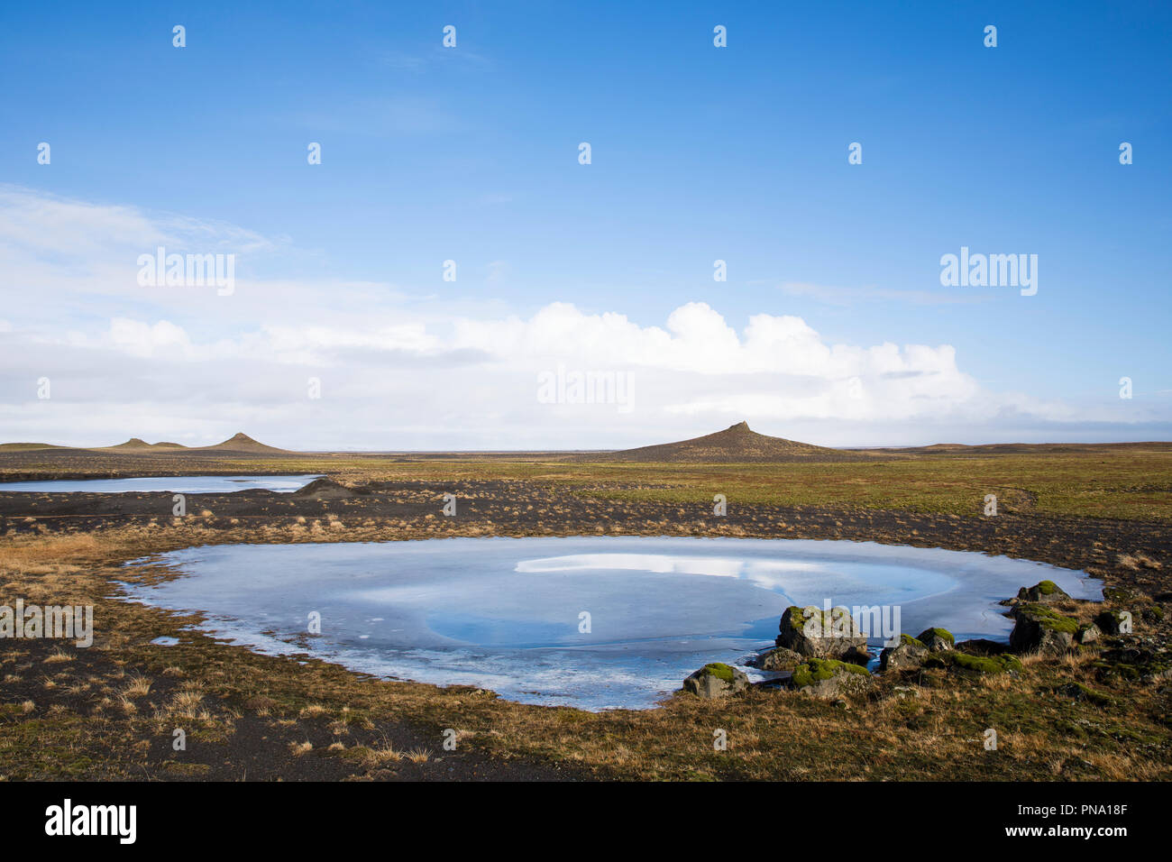 Glacial melt pond at Myrdalssandur, an outwash plain in Vatnajokull National Park, volcanic crater cones behind, South Iceland Stock Photo