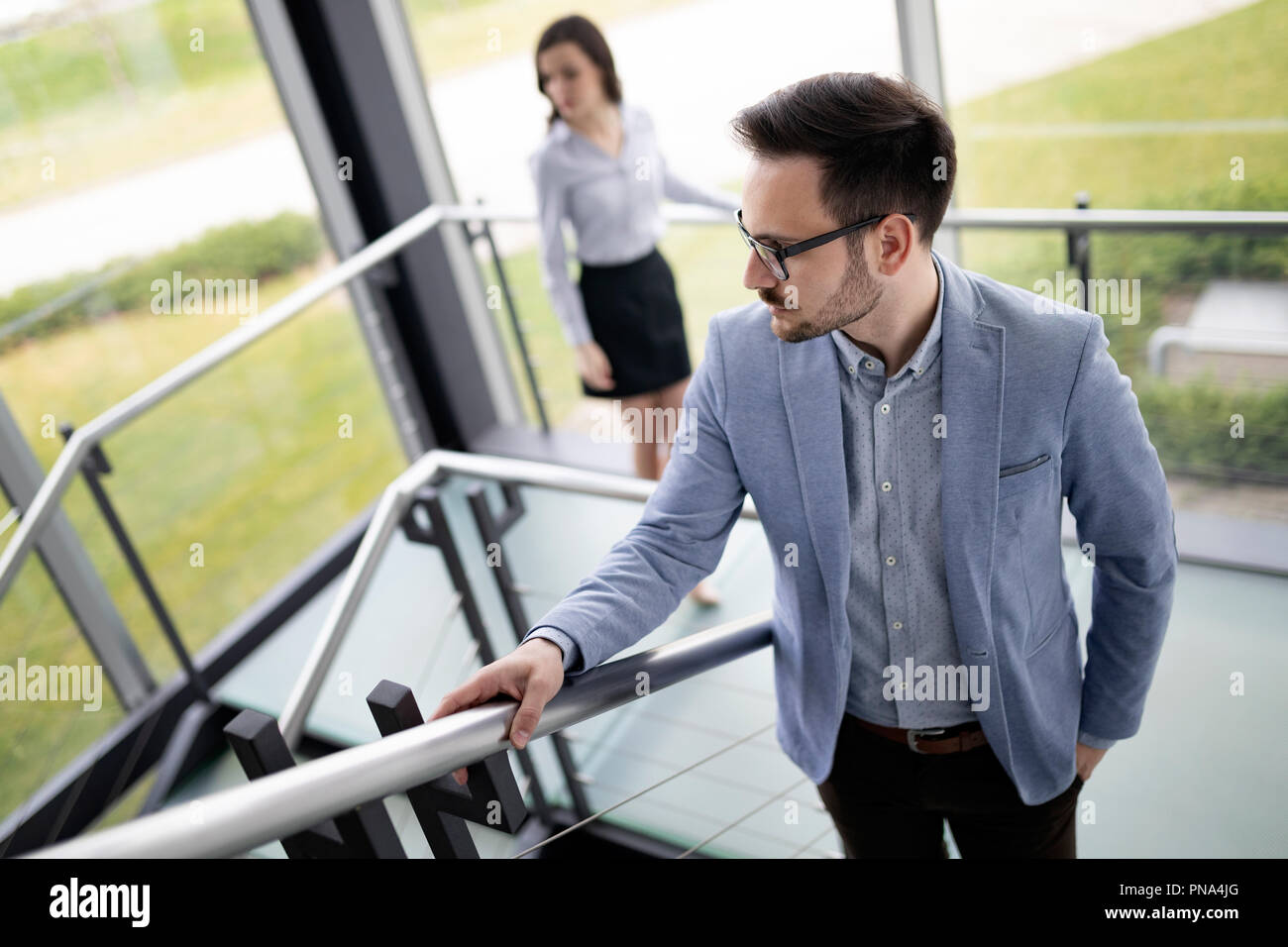Modern business people walking on stairs in glass hall in office ...