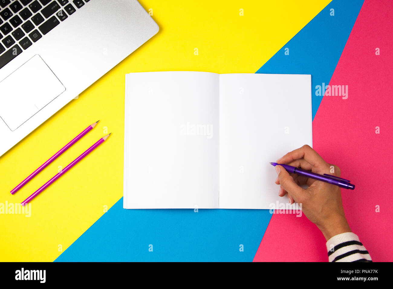 Woman hand writing in notebook on colorful background Stock Photo