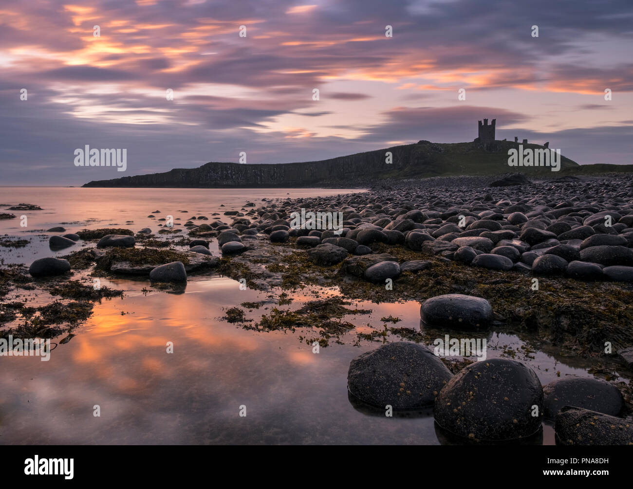 Dunstanburgh Castle at sunrise, Northumberland coast, England, UK Stock Photo