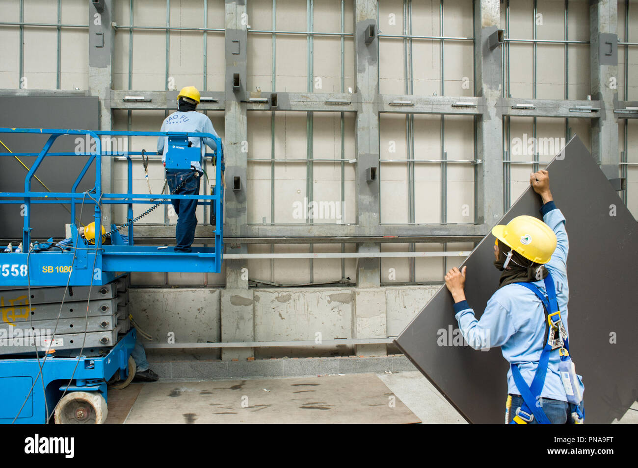 SINGAPORE – february 25, 2011 : workers installing glass plates on a new building Stock Photo
