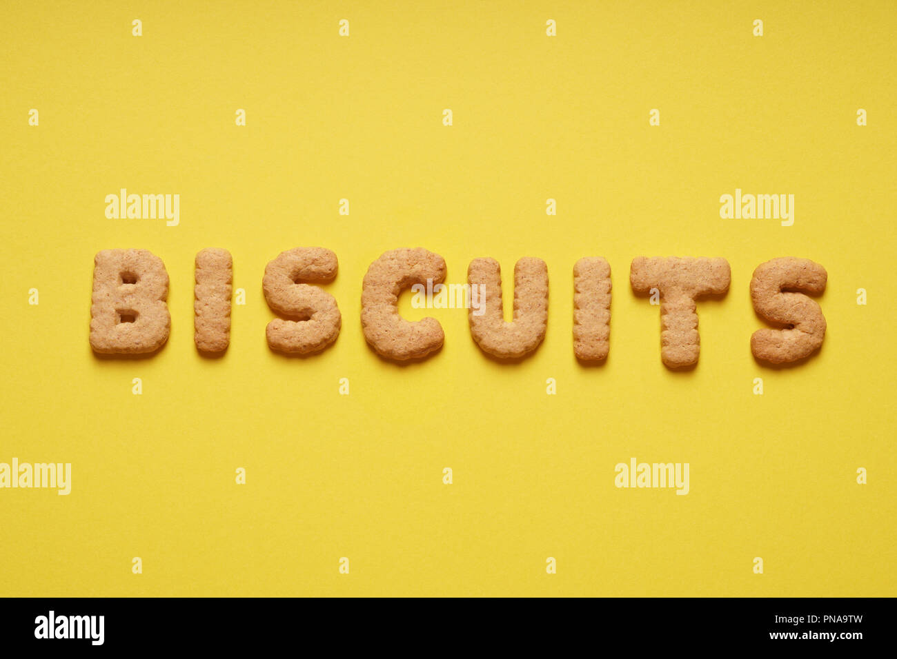 biscuits word spelled out with biscuit letters or characters on yellow paper background Stock Photo