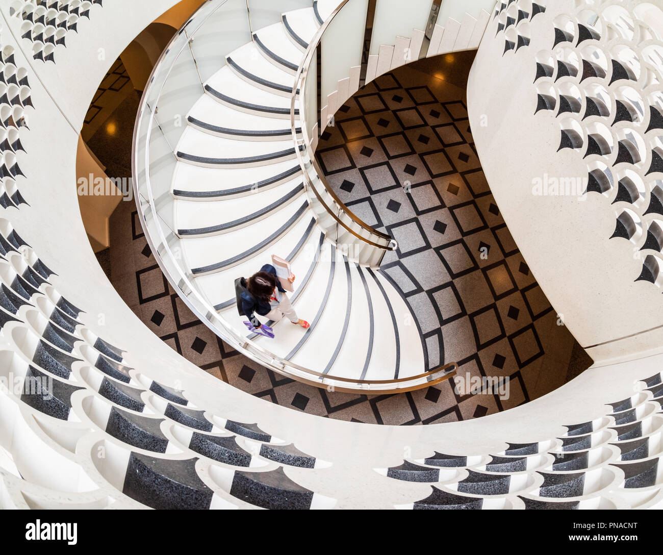 View from above of woman walking down spiral staircase at the Tate Modern in London Stock Photo