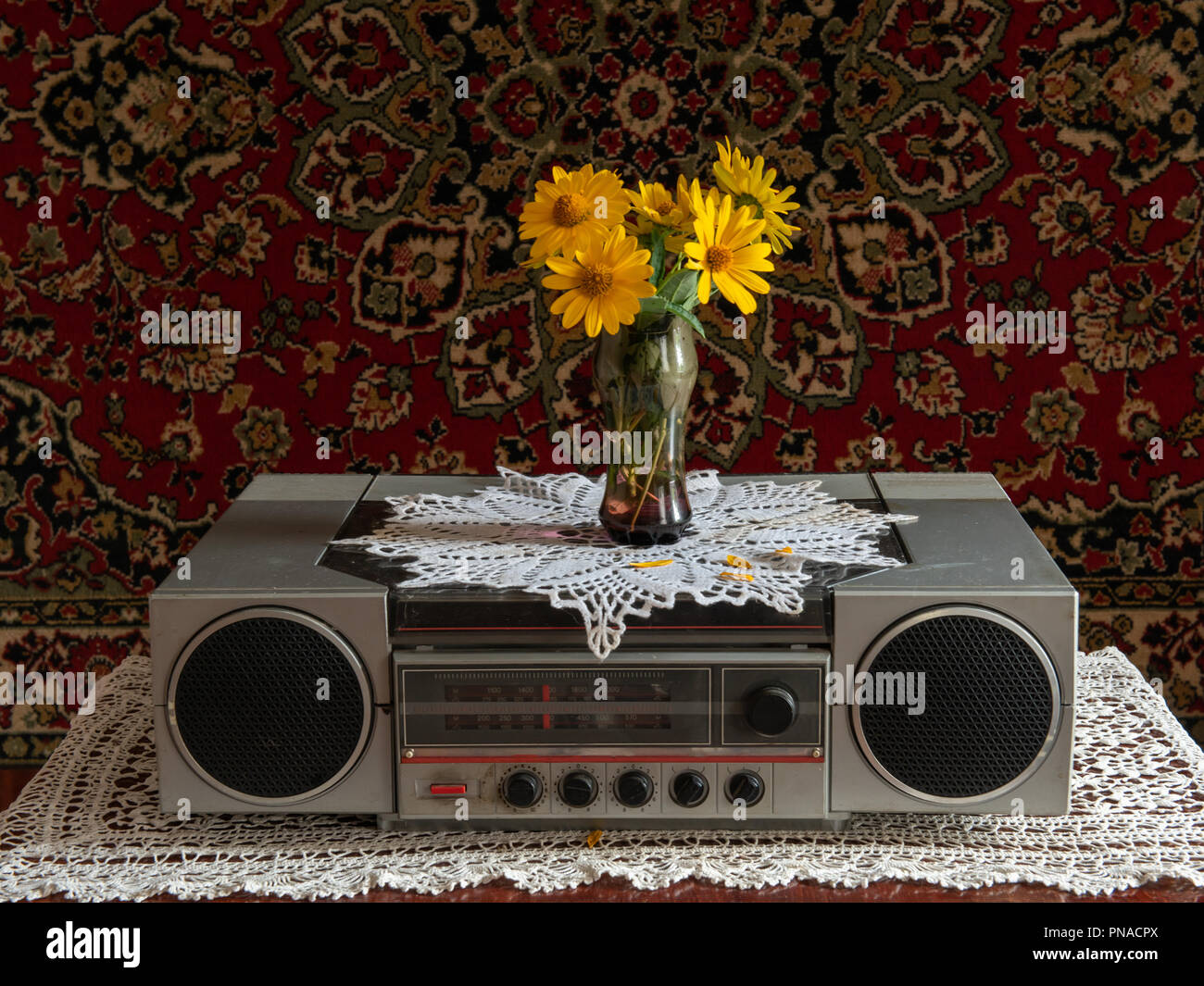 Old radio on the table with a clock and a vase of flowers Stock Photo