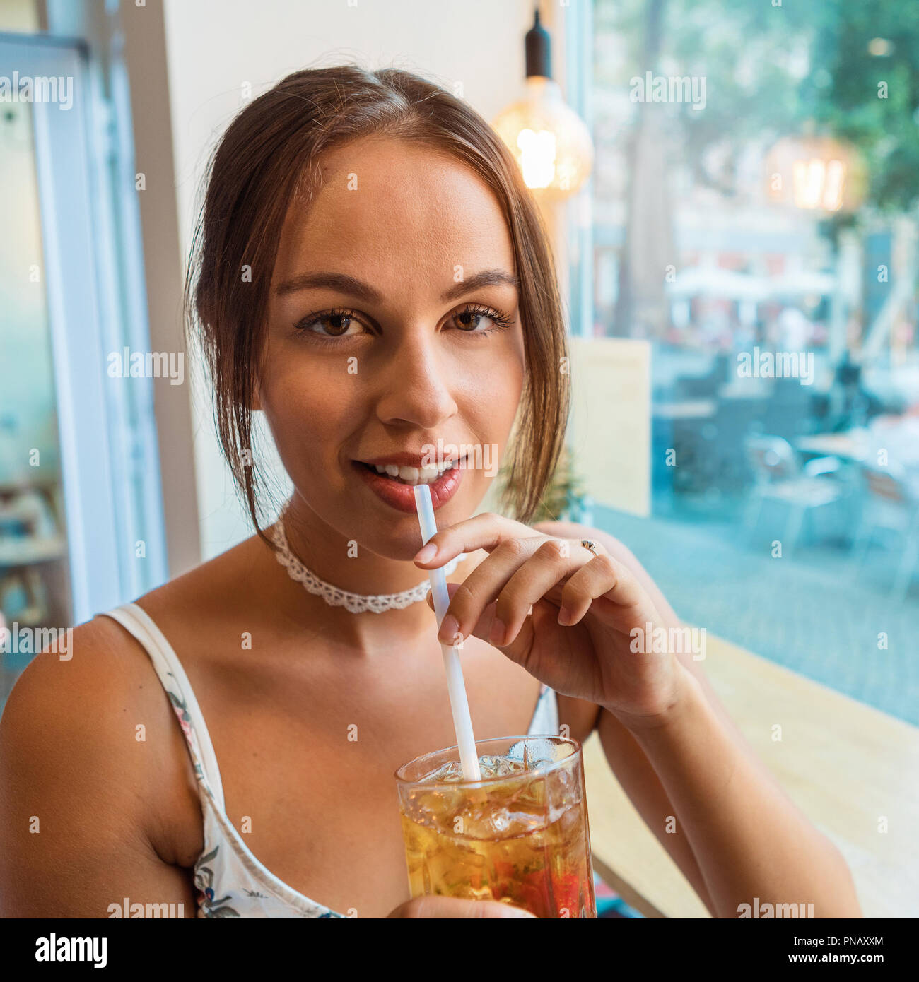 Young brunette woman having ice tea at a café Stock Photo