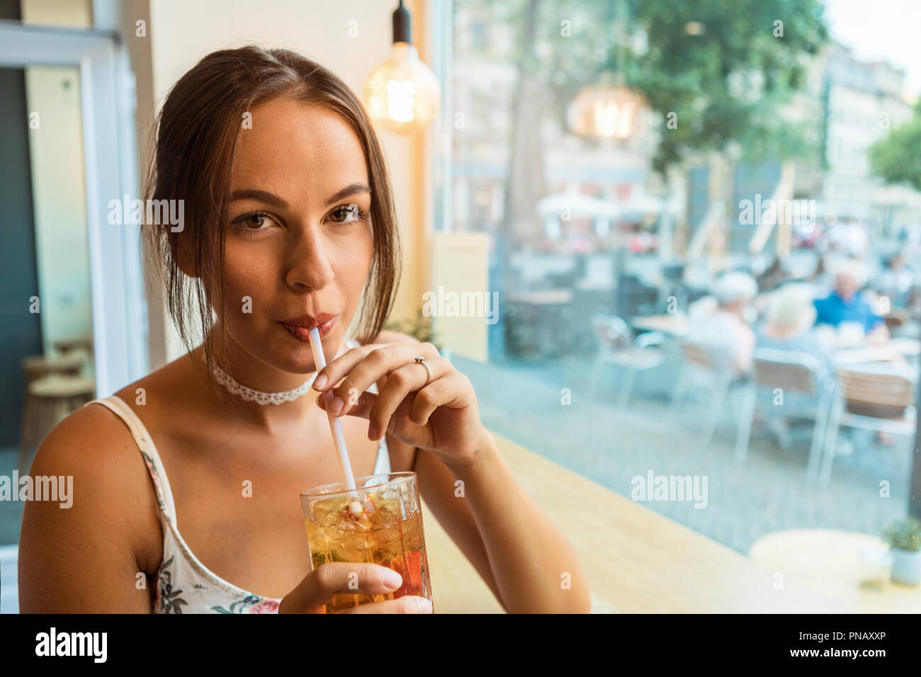 Young brunette woman having ice tea at a café Stock Photo