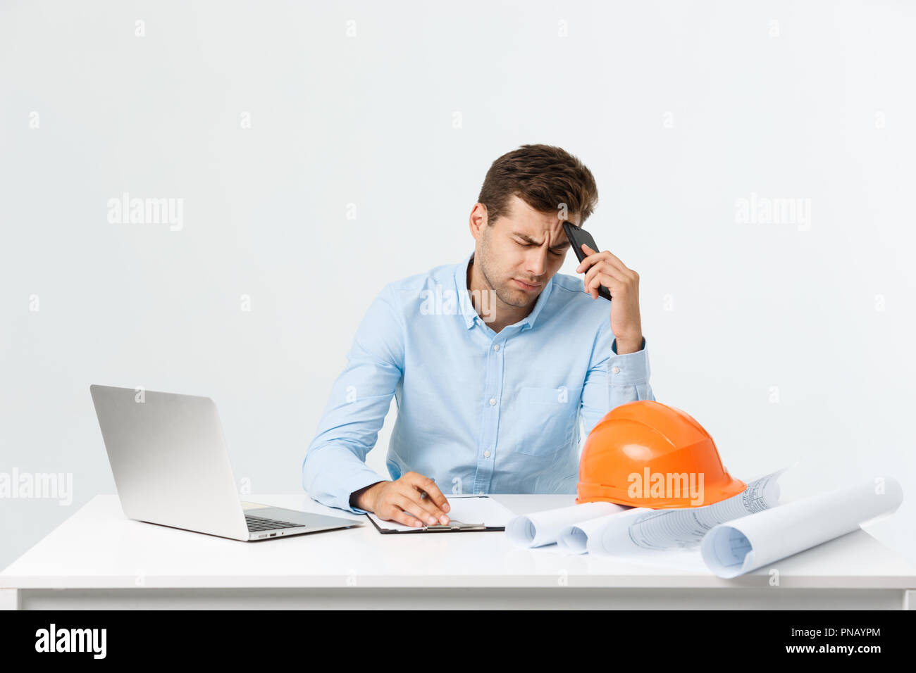 Focused serious hardworking engineer busy working on big architectural project late, sitting at his workspace using digital tablet pc. People, job, occupation and profession concept Stock Photo