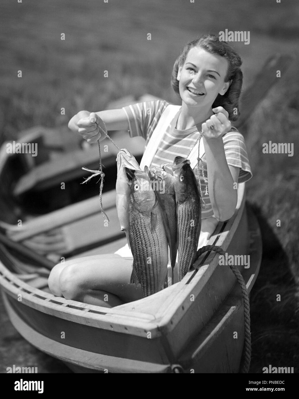 1940s Smiling Young Woman Sitting In Row Boat Looking At Camera Holding Up Nice Catch Of Fish A2809 Deb001 Hars Celebration Females Proud Rural Home Life Nature Copy Space Catch Half Length