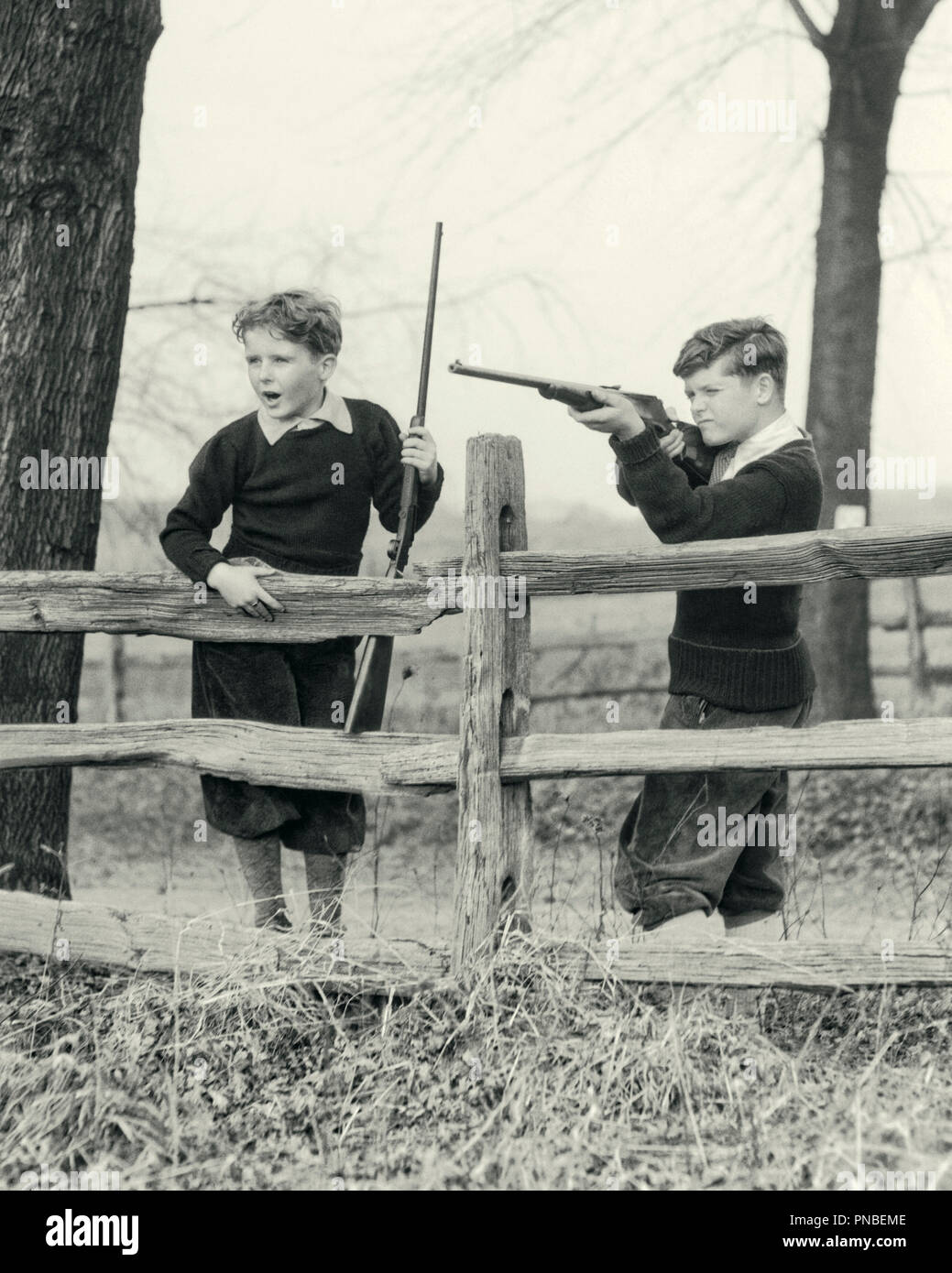 1930s TWO PRETEEN BOYS IN PLUS FOURS AND AUTUMN SWEATERS BEHIND SPLIT RAIL FENCE SAFELY PLINKING SHOOTING 22 CALIBER RIFLES  - a3260 HAR001 HARS CONFIDENCE B&W FREEDOM HAPPINESS ADVENTURE TROUSERS AND ENJOYING KNOWLEDGE RECREATION IN PRETEEN SIBLING SWEATERS SPLIT RAIL CONCEPTUAL RESPONSIBLE RIFLES PLUS FOURS AIMING FIREARM FIREARMS GROWTH JUVENILES PRE-TEEN PRE-TEEN BOY TOGETHERNESS 22 CALIBER BLACK AND WHITE BREECHES CAUCASIAN ETHNICITY HAR001 OLD FASHIONED PRACTICING Stock Photo