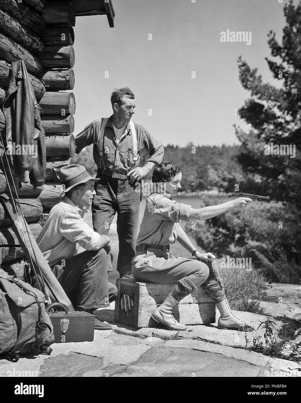 1930s TWO MEN CAMP GUIDES WATCHING INSTRUCTING YOUNG WOMAN SHOOTING 22 CALIBER PISTOL OUTSIDE RUSTIC MOUNTAIN LOG CABIN - a5518 HAR001 HARS FEMALES RURAL FULL-LENGTH LADIES PERSONS MALES CONFIDENCE B&W TIME OFF RUSTIC ADVENTURE LEISURE PROTECTION STRENGTH GETAWAY CHOICE INSTRUCTOR KNOWLEDGE POWERFUL DIRECTION PRIDE AUTHORITY FIRING HOLIDAYS INSTRUCTING CONNECTION CONCEPTUAL INSTRUCTION GUIDE GUIDES STYLISH AIMING FIREARM FIREARMS MID-ADULT MID-ADULT MAN MID-ADULT WOMAN PISTOL RELAXATION VACATIONS YOUNG ADULT WOMAN BLACK AND WHITE CAUCASIAN ETHNICITY HAR001 LOG CABIN OLD FASHIONED Stock Photo