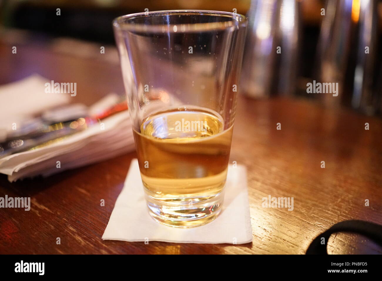 A half empty beer sits on a bar Stock Photo