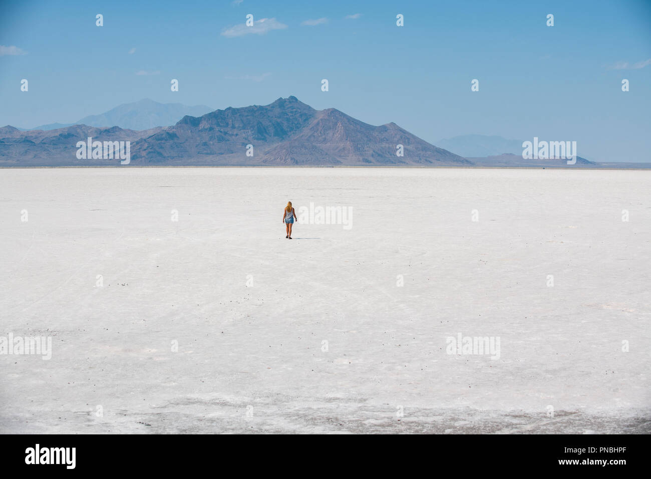 A blonde woman walks across Bonneville Salt Flats, Tooele County, Utah, USA. Stock Photo