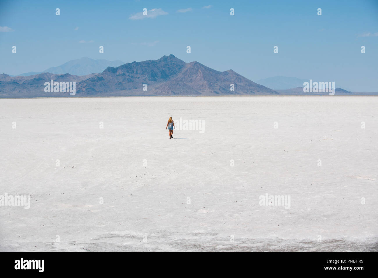 A blonde woman walks across Bonneville Salt Flats, Tooele County, Utah, USA. Stock Photo