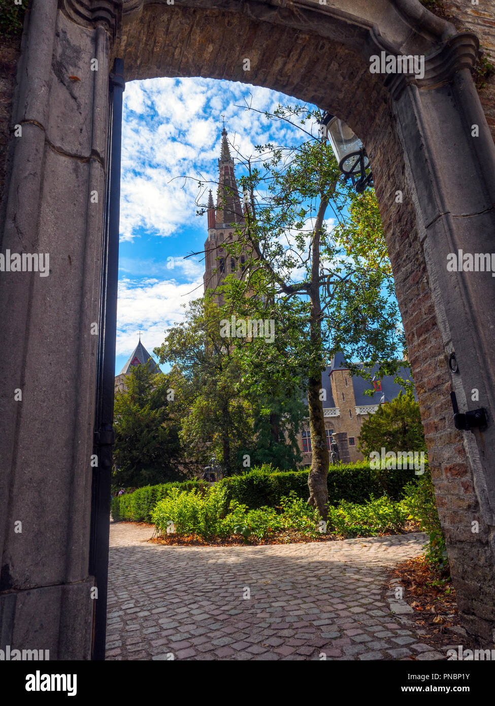 View throught a gate of the tower of Church of Our Lady and Arentshof square - Bruges, Belgium Stock Photo