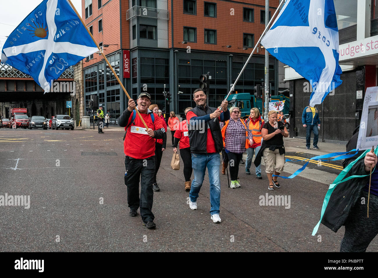 Two members of the Scotland recovery walk fly Saltire flags with print on them during the walk. Stock Photo