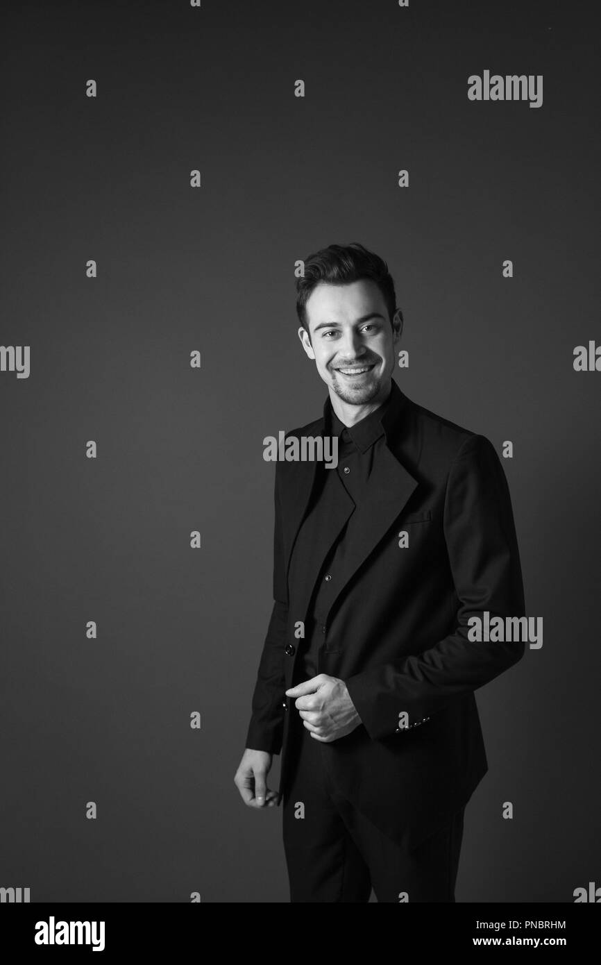 Young handsome man in a black suit, smiling and looking at the camera ...
