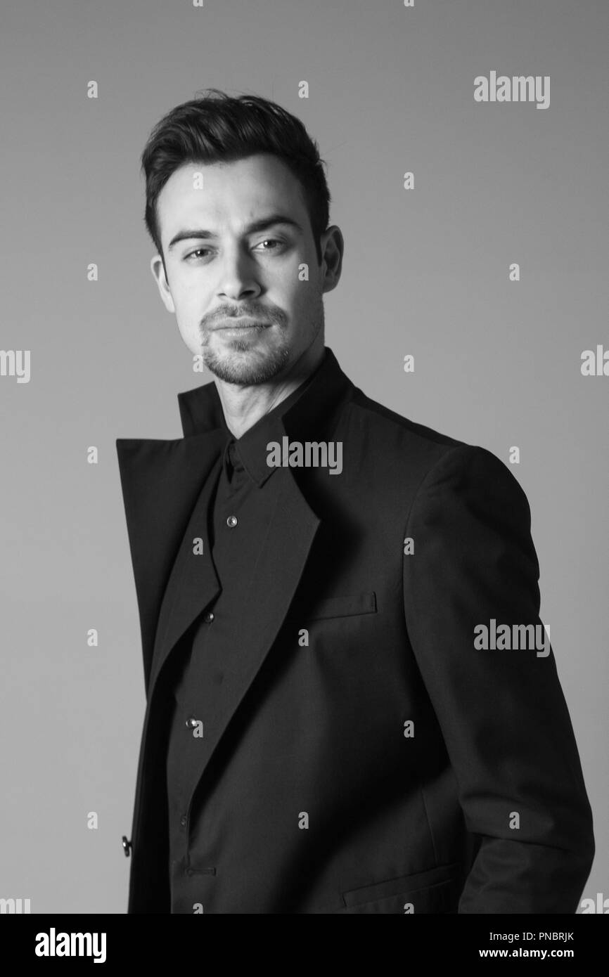 Portrait of a young handsome man in a black suit, standing and ...