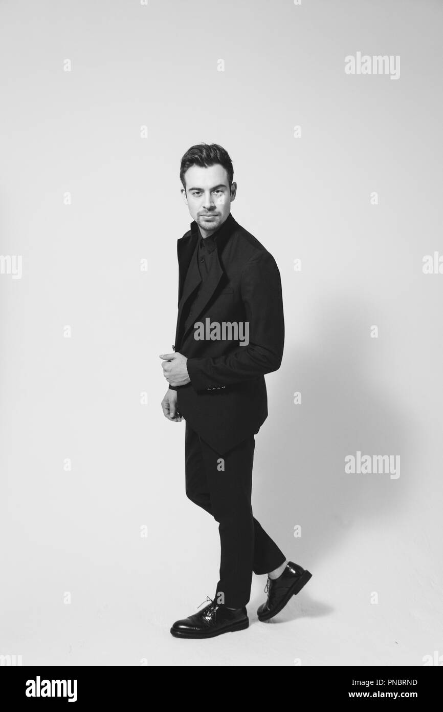 Portrait of a young handsome man in a black suit, standing and ...