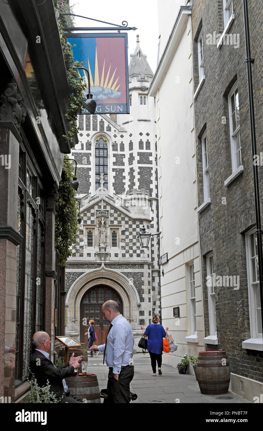 Men drinking beer outside The Rising Sun pub with a view of St Bartholomew the Great church in Smithfield London EC2 England UK  KATHY DEWITT Stock Photo